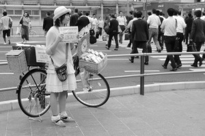 Photo d'une jeune japonaise qui distribue des mouchoirs publicitaires. Prise à Fukuoka, 2012 par Maria Petersen